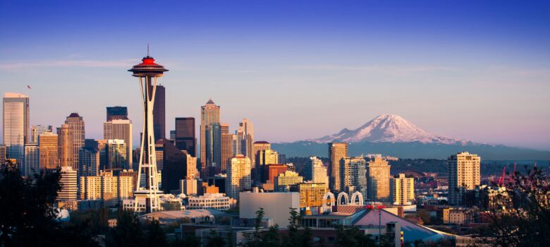 The Seattle city skyline with Mount Rainer in the distance on the right and the Seattle Needle in the foreground on the left.